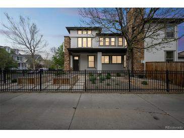 Charming two-story home featuring stone accents, large windows, and a well-maintained front yard with a black iron fence at 3366 Willow St, Denver, CO 80238