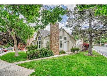 Charming home featuring a brick chimney, lush green lawn, and mature trees in a well-maintained front yard at 1148 S Ventura Cir # H, Aurora, CO 80017