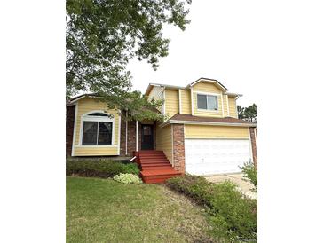 Inviting two-story home with a well-maintained front yard, attached two-car garage, and charming red brick accents at 10525 Hobbit Ln, Westminster, CO 80031