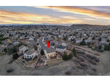 Beautiful aerial view of a suburban home with a large deck, landscaped yard and mountain views at sunset at 7360 Almandine Ct, Castle Rock, CO 80108