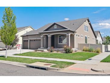 Charming home featuring manicured lawn, inviting front porch, and a three-car garage, set under a clear blue sky at 19802 E 54Th Ave, Denver, CO 80249