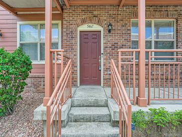 Charming brick home entrance featuring a red front door, concrete steps, and decorative railings at 5467 Zephyr Ct # 5467, Arvada, CO 80002