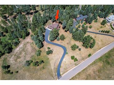 An aerial view of the home showing the long driveway, the surrounding trees and neighborhood at 8171 S Homesteader Dr, Morrison, CO 80465