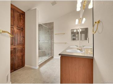 Bright bathroom featuring a double vanity, glass enclosed shower, and built-in storage cabinet at 4042 E Hinsdale Cir, Centennial, CO 80122