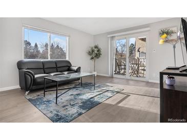 Bright living room with balcony access and modern glass coffee table at 7375 E Quincy Ave # 204, Denver, CO 80237