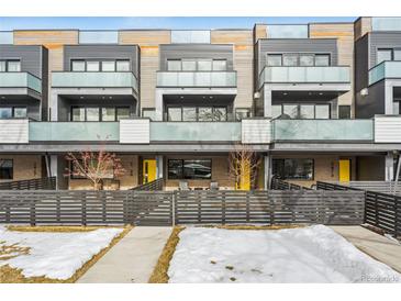 Modern townhome with a yellow front door and a sleek, fenced yard at 2471 Walnut St, Boulder, CO 80302