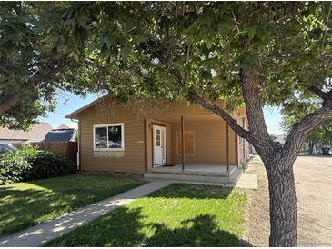 Charming single-story home with a covered front porch and mature trees at 1000 Denver Ave, Fort Lupton, CO 80621