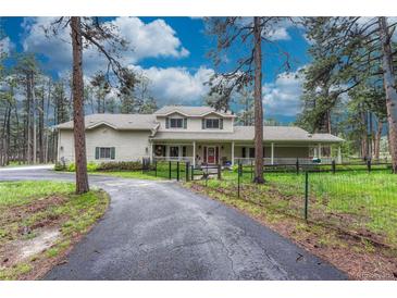 Charming home with a long driveway, fenced yard, and inviting front porch at 18470 Canterbury Dr, Monument, CO 80132