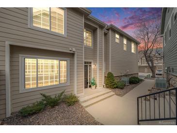 Inviting townhome showcases manicured landscaping, complemented by the warm hues of the sunset sky at 1311 Carlyle Park Cir, Highlands Ranch, CO 80129