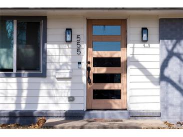 Modern front door with glass panes, sconces, and visible house number creates a welcoming entrance to this charming home at 555 W Peakview Ave, Littleton, CO 80120