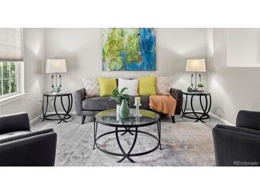 Comfortable living room with stylish gray sofa, colorful pillows, and a glass coffee table complemented by modern side tables at 306 Monares Ln, Erie, CO 80516