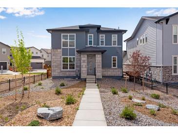 Beautiful two-story home with gray siding, stone accents, manicured landscaping, and inviting walkway to the front door at 3314 N Haleyville Ct, Aurora, CO 80019