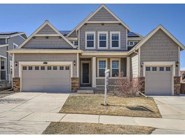 Inviting two-story home featuring a charming front porch, a two-car garage, and professionally landscaped front yard at 10371 Harrisburg St, Parker, CO 80134