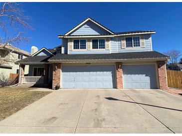 Charming two-story blue home with a three-car garage and well-manicured lawn at 4992 S Elkhart Ct, Aurora, CO 80015