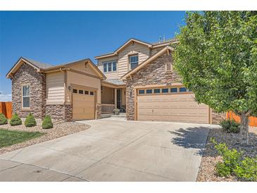 Charming two-story home with a stone and siding exterior, driveway, mature tree and multiple garage doors at 5923 S Jamestown Ct, Aurora, CO 80016