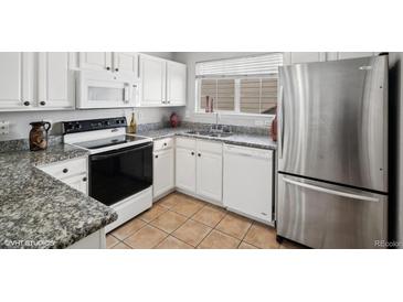 Bright kitchen features granite countertops, stainless steel refrigerator, and white cabinetry at 5095 S Newcombe Ct, Littleton, CO 80127