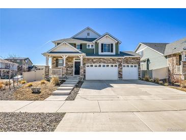Inviting two-story home featuring stone accents, a spacious three-car garage, and landscaped front yard at 4407 N Quemoy St, Aurora, CO 80019