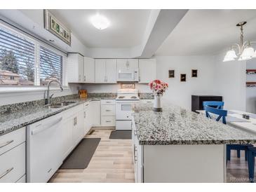 Bright kitchen features white cabinetry, granite countertops, stainless steel sink, and modern appliances at 1294 S Troy St, Aurora, CO 80012