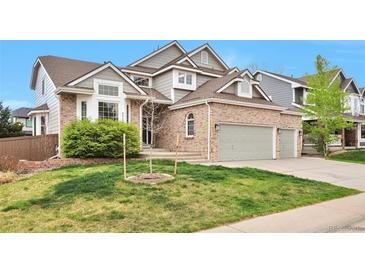Charming two-story home featuring a brick facade, a well-manicured lawn, and a spacious two car garage at 8958 Forrest Dr, Highlands Ranch, CO 80126
