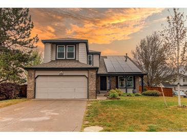 Charming two-story home with a brick-accented garage, solar panels and well-manicured front lawn against a colorful sunset at 6647 Lynx Cv, Lone Tree, CO 80124
