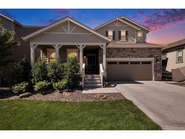 Charming two-story home featuring stone accents, a covered porch, and a well-maintained lawn at sunset at 6193 Saddle Bow Ave, Parker, CO 80134