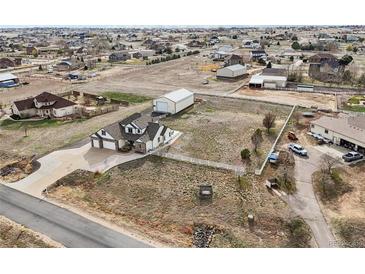 Expansive lot featuring home with attached garages, additional storage building and white perimeter fence at 16665 Kenuil St, Brighton, CO 80603