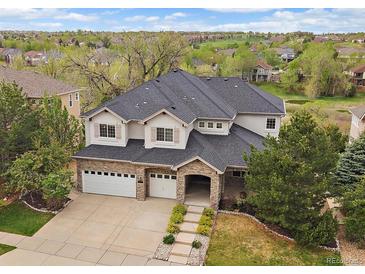 Charming two-story home features a three-car garage, stone accents, and a well-manicured lawn at 7829 S Coolidge Way, Aurora, CO 80016