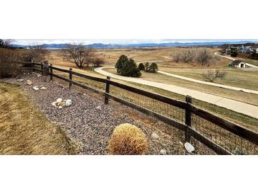 Rustic yard with a wooden fence, walking path, and distant mountain views creates a serene natural retreat at 227 Powderhorn Trl, Broomfield, CO 80020