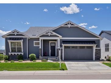 Charming one-story home featuring manicured lawn, gray siding, stone accents, and an attached two-car garage at 10258 W Coal Mine Pl, Littleton, CO 80127