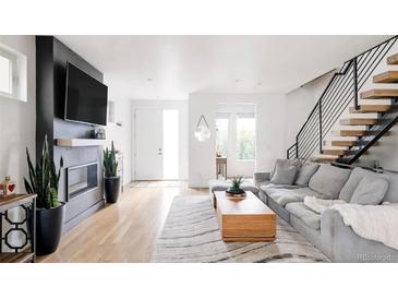 Bright living room features a fireplace, flatscreen television, and modern staircase to the second level at 2685 S Acoma St, Denver, CO 80223