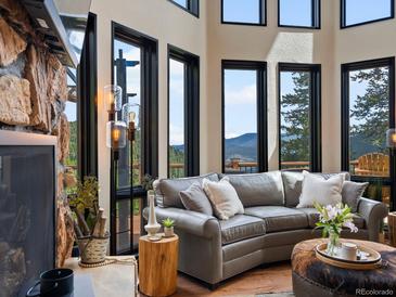 Inviting living room with stone fireplace and large windows offering mountain views at 1194 Snyder Mountain Rd, Evergreen, CO 80439