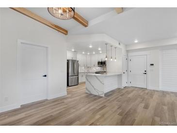 Bright open kitchen features white cabinets, stainless appliances, and an island with waterfall countertop at 1308 Snowberry Ln # 302, Louisville, CO 80027