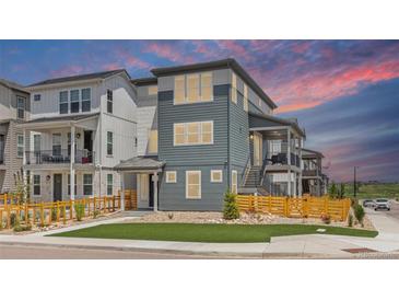 Stylish three-story home with muted-blue siding and wooden fence under a gorgeous pink and blue sky at 11000 Shining Star Cir, Parker, CO 80134