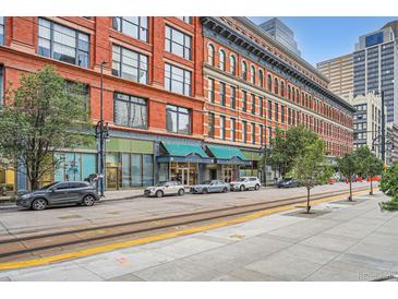 Street view of a beautiful brick apartment building with storefronts and residences, showcasing urban living at 1555 California St # 304, Denver, CO 80202