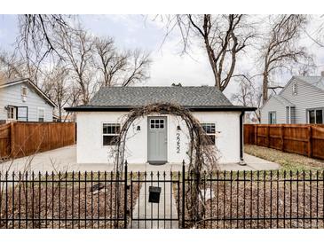 Charming home featuring a white exterior, gray door, and decorative wrought iron fence and gate at 2252 Harlan St, Edgewater, CO 80214