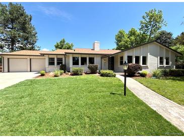 Charming ranch style home with beautiful lawn, landscaped yard, and attached two car garage at 9451 E Evans Pl, Denver, CO 80231