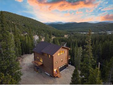 Stunning exterior of the mountain home nestled in a forest with a charming deck and welcoming front porch at 57 Overlook Ct, Idaho Springs, CO 80452