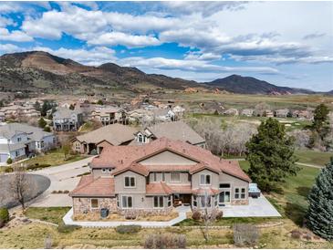 Sprawling two-story home with a stone and stucco exterior, complemented by a lush, landscaped yard and mountain views at 16226 River Haven Way, Morrison, CO 80465