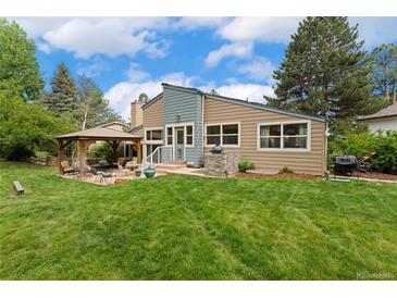 Landscaped backyard with large grassy area, outdoor kitchen and a covered patio with seating area at 6621 E Peakview Pl, Centennial, CO 80111
