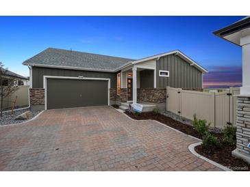 Charming single-story home featuring stone accents, a two-car garage, and a brick driveway at 5142 N Quemoy Ct, Aurora, CO 80019