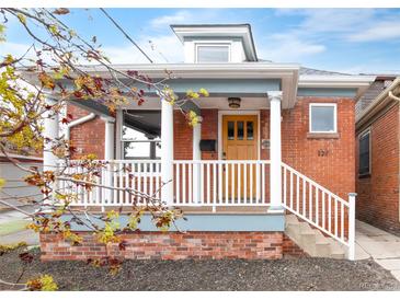 Charming brick home featuring a covered front porch, white columns, and manicured landscaping at 120 Cherokee St, Denver, CO 80223