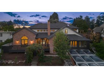 Charming two-story home with a brick exterior, dark roof, a lush garden entrance and manicured landscaping at 375 S University Blvd, Denver, CO 80209