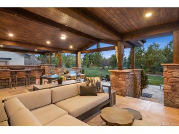 Covered outdoor living space featuring a stone bar, dining, and lounge area with a wood ceiling at 6111 Huron Pl, Castle Rock, CO 80108