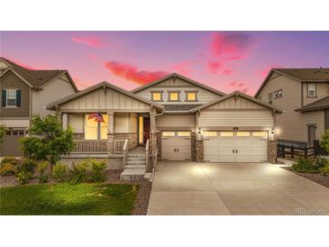 Charming home featuring a well-manicured lawn, inviting porch, and convenient two-car garage with a beautiful sunset at 8814 S Winnipeg Ct, Aurora, CO 80016