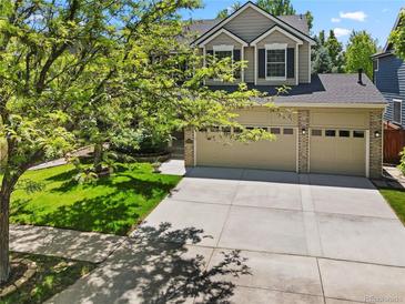 Charming two-story home featuring a well-manicured lawn, mature trees, and an attached two car garage at 6310 W Sumac Ave, Littleton, CO 80123