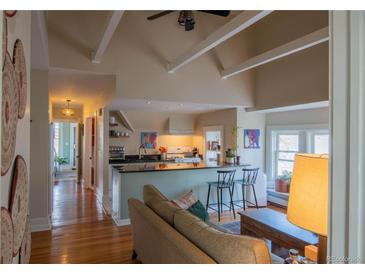 Inviting living room flows into a kitchen featuring an island with barstool seating and hardwood floors at 1435 Vine St # 5, Denver, CO 80206