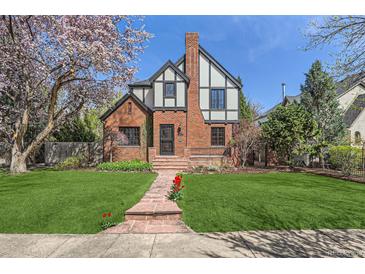 Charming Tudor-style home with brick facade, lush lawn, and blooming tree at 1650 Locust St, Denver, CO 80220