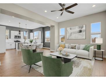 Bright, open-concept living room with modern decor and hardwood floors connected to the modern kitchen and a ceiling fan at 7870 W 43Rd Pl, Wheat Ridge, CO 80033