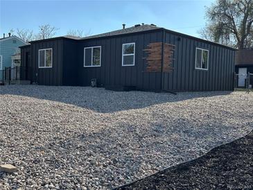 Beautiful exterior view of home with dark siding and gravel landscaping with bright white framed windows at 1285 Roslyn St, Denver, CO 80220