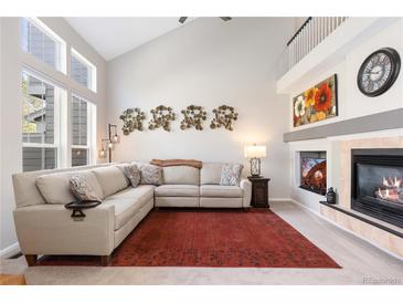 Bright living room featuring a fireplace, high ceilings, large windows and comfortable seating, perfect for relaxing and entertaining at 10183 Grove Loop # D, Westminster, CO 80031